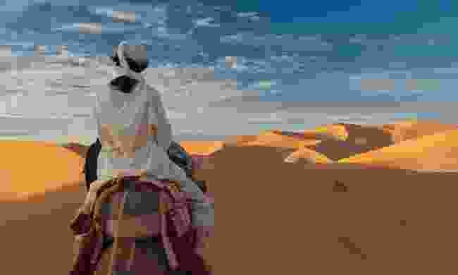 Riding a camel in the Sahara desert (Dreamstime)