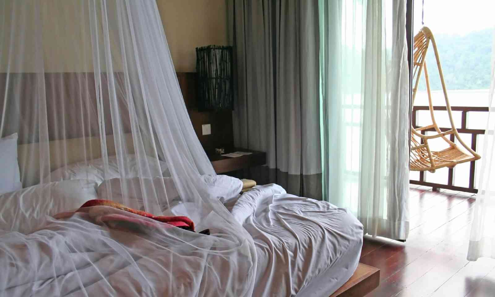 Tropical bed with mosquito net and balcony (Shutterstock)