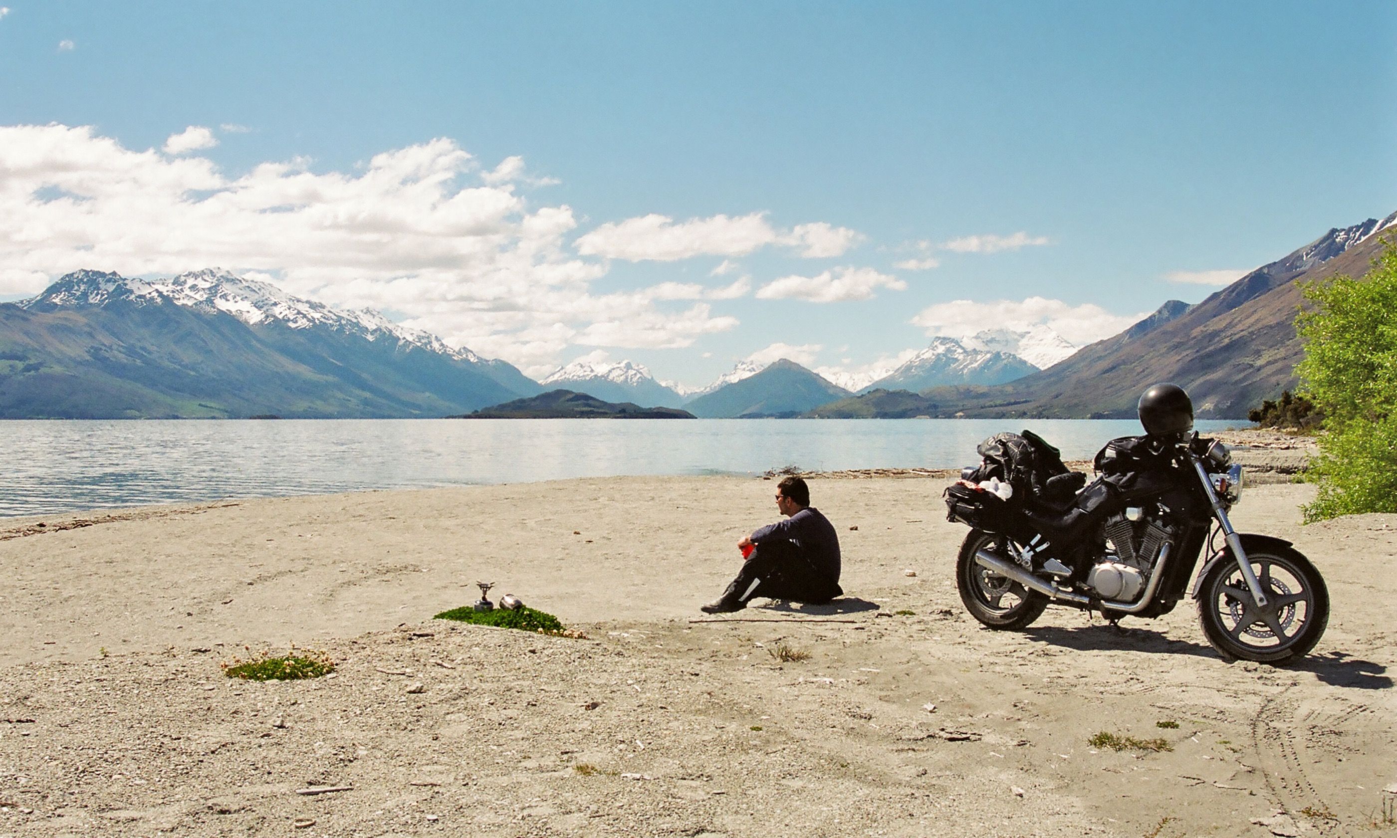 Motorcyclist resting beside a lake (Dreamstime)